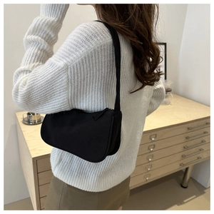 Minimalist black canvas underarm bag shown on shoulder for a stylish commuter look