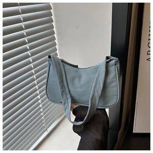 Detail of light blue canvas underarm bag showing fine stitching and minimalist structure