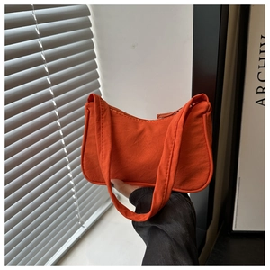 Detail view of a bright orange nylon baguette bag with textured surface and sleek zipper