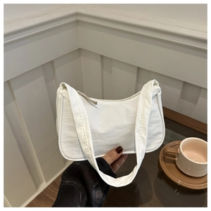 Close-up of white minimalist crescent bag featuring pleated fabric and zipper closure