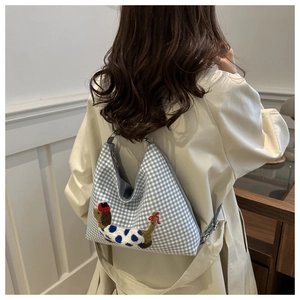 Detail of blue gingham crossbody bag with chenille dachshund embroidery on fabric