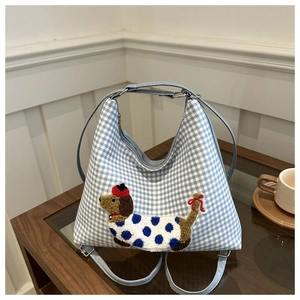 Close-up of blue plaid tote bag featuring a 3D embroidered dachshund with polka dot dress