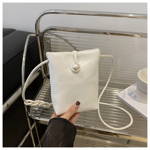 Detail of white mini crossbody bag featuring a large pearl buckle and woven strap details