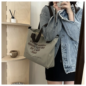 Mirror selfie showing large canvas tote bag with letter print and dual shoulder straps
