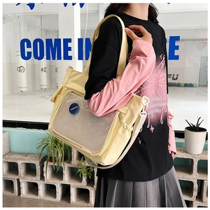 Detailed view of yellow tote bag featuring mesh pocket and fashion badge decoration