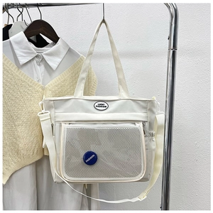 Detail of off-white tote bag with front mesh pocket and adjustable shoulder strap