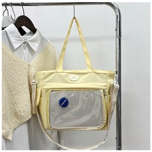 Detail of light yellow tote bag featuring a clear PVC pocket and mesh inner compartment