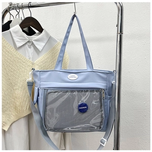 Detail of light blue nylon tote bag showing transparent mesh pocket and brand logo patch
