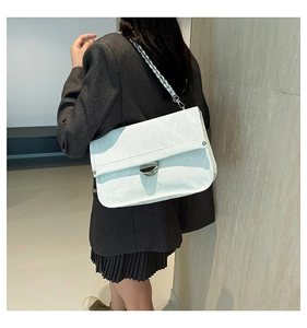 Detailed view of white pleated leather bag with gold chain strap and metal clasp on model