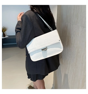 Detailed view of white leather shoulder bag with silver chain strap and metal clasp closure