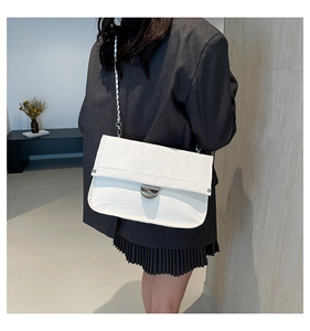 Detailed view of a white textured shoulder bag featuring silver clasp and chain strap
