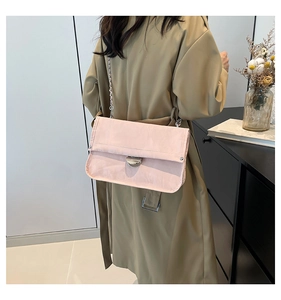Detail of pink chain bag with silver buckle worn over a beige trench coat