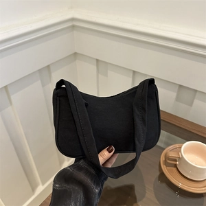 Minimalist black fabric underarm bag with sleek curved design and zip closure for women