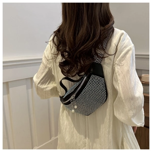 Détail du sac bandoulière avec strass brillants, sangle rayée et pendentif en perles