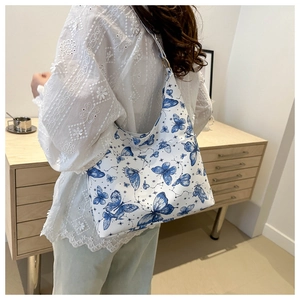 Close-up of canvas tote bag featuring navy blue butterfly prints and wide shoulder strap