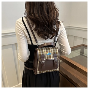 Détail du mini sac à dos à carreaux vintage avec garniture en cuir et patch d'ours sur modèle