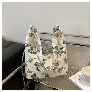 Detail of butterfly print tote bag with gold ring buckle and side pocket on a sofa