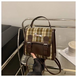 Détail du sac à dos vintage à carreaux avec broderie de teckel et sangles à boucles en cuir