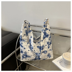 Detail of the blue butterfly print and metal ring attachment on a white tote bag