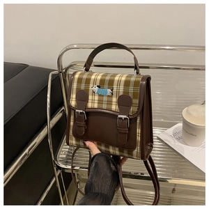 Gros plan d'un mini sac à dos à carreaux avec broderie teckel et sangles à boucles en cuir