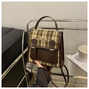 Détail du sac à dos vintage à carreaux avec garniture en cuir brun et broderie chien