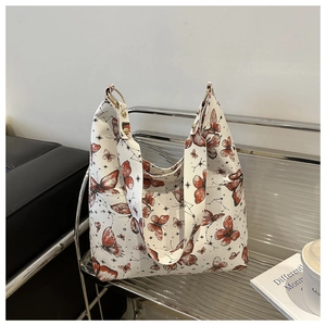 Detailed close-up of white tote bag featuring butterfly print and gold ring metal accents