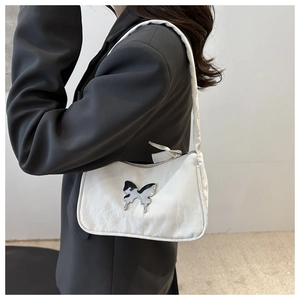 Détail du sac sous le bras blanc plissé avec grande boucle papillon en métal argenté