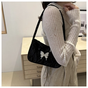 Detailed view of black pleated fabric underarm bag with silver butterfly metal buckle