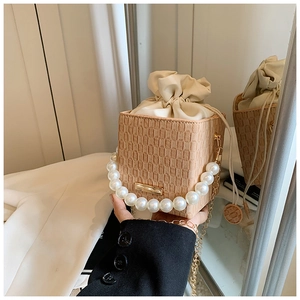 Detail der beigen Beuteltasche mit Webstruktur, Perlengriff und goldener Kette