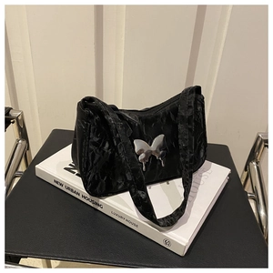 Close-up of pleated black shoulder bag featuring a silver metal butterfly ornament