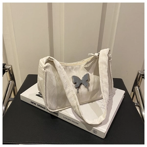 Detail of cream pleated shoulder bag featuring a silver metal butterfly and marble texture