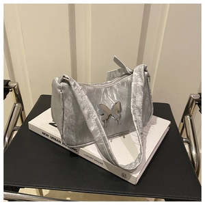 Close-up of silver butterfly metallic underarm bag with pleated texture on leather chair