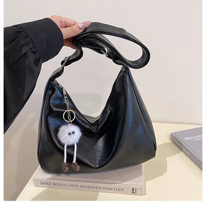 Detail einer großen mattschwarzen PU-Leder Hobo-Tasche mit süßem Plüsch-Anhänger