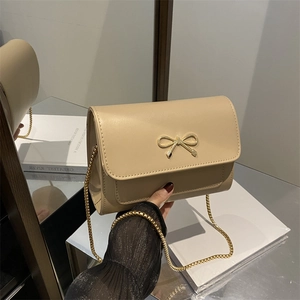 Elegant beige crossbody bag with gold bow clasp and metallic chain strap