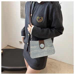 Close-up of light blue glitter crossbody bag with brown leather strap and buckle