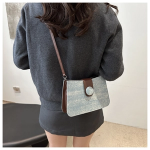 Detail of glittery silver fabric and brown leather straps on retro crossbody bag