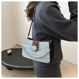 Détail d'un sac bandoulière vintage en denim avec finitions en cuir marron élégant