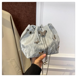 Detail of metallic silver bucket bag with 3D butterfly ornament and pearl drawstring charm