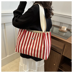 Détail du sac fourre-tout en toile rayé rouge et blanc avec bandoulière sur l'épaule