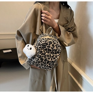 Dettaglio mini zaino leopardato con ciondolo a forma di panda peluche su un cappotto beige