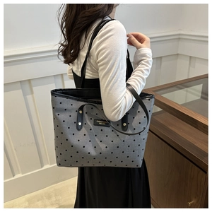 Polka dot canvas tote bag with black leather straps shown on model for size and scale
