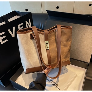 Detailed view of the canvas tote bag with brown leather trim and golden metal turn-lock