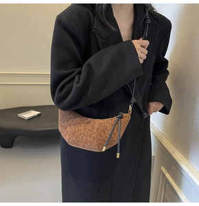 Detailed view of leopard print croissant bag with stitched texture on black blazer