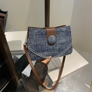Chic blue denim shoulder bag with brown leather accents and a bold silver metal chain