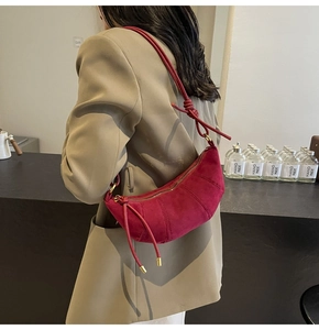 Detail of fuchsia suede crescent bag featuring knotted straps and soft matte texture