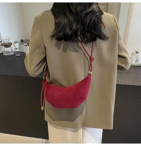 Detail of burgundy crescent croissant bag in suede finish with adjustable strap and stitching