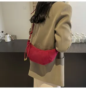 Detail showing burgundy suede croissant bag with stitching and gold metal buckle