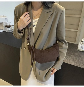 Detail of a brown suede croissant crossbody bag showing fine texture and crescent shape