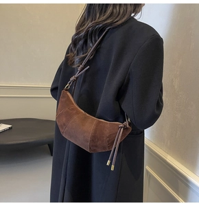 Detailed view of brown suede croissant bag featuring stitched panels and a leather knot strap