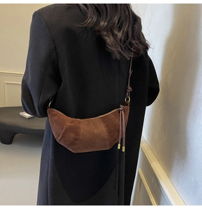 Brown suede croissant bag styled on a model showing crossbody drape and texture